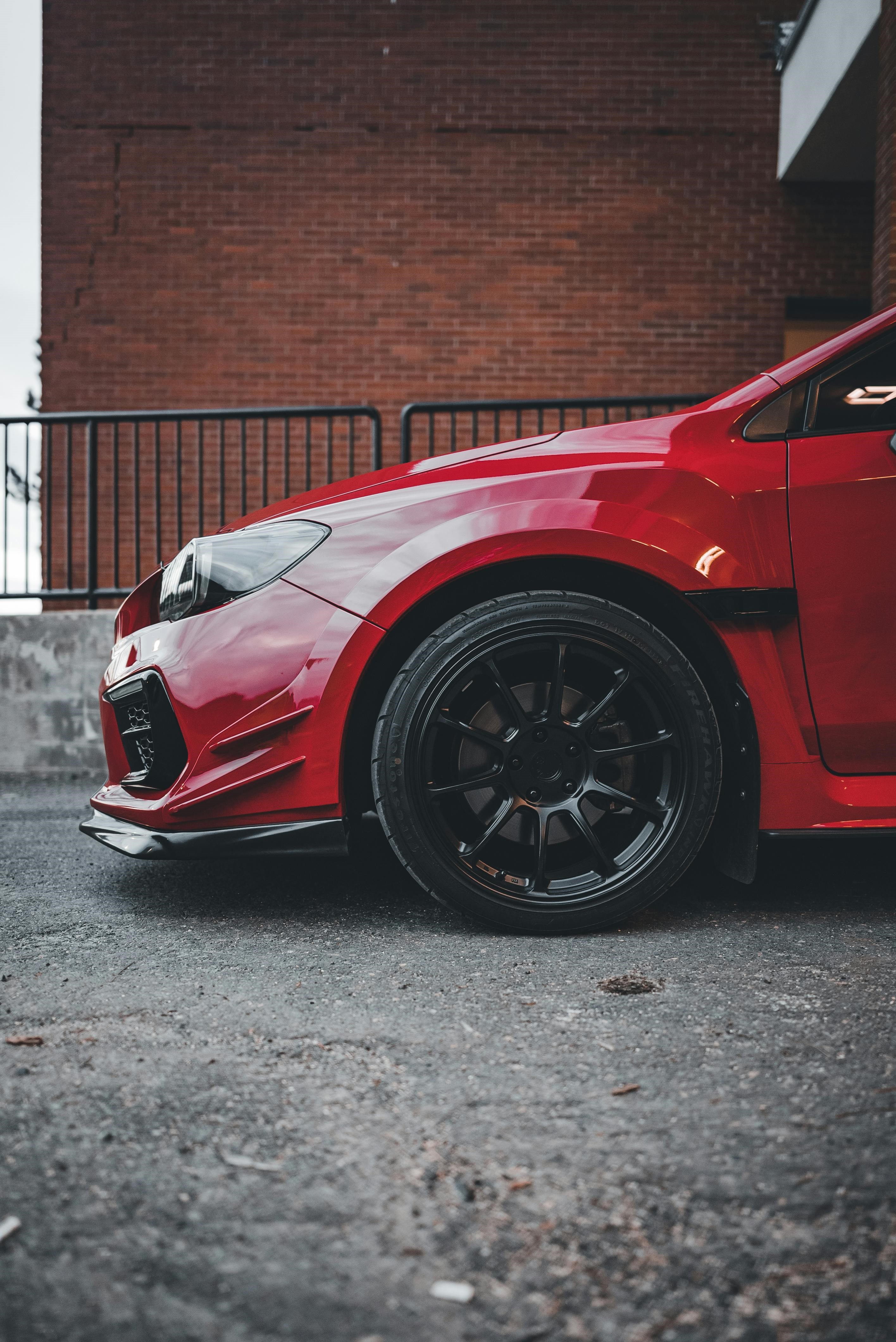 Red Subaru WRX with black powder-coated wheels.